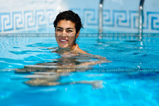 Happy young woman relaxing in swimming pool. Smiling girl with healthy tanned skin and wet hair enjoying Summer Sun at pool edge.. Happy young woman relaxing in swimming pool. Стоковое фото, агентство Ingram Publishing / Фотобанк Лори
