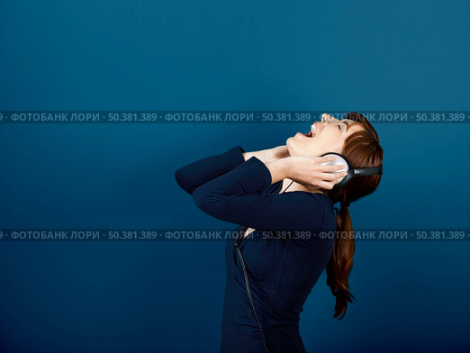 Happy young woman singing and listen music with headphones. Стоковое фото, агентство Ingram Publishing / Фотобанк Лори