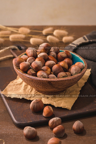 Hazelnuts in a ceramic bowl on a rustic kitchen countertop. Стоковое фото, агентство Ingram Publishing / Фотобанк Лори