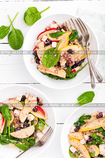 Healthy fruit and berry salad with fresh apples, cranberries, walnuts, italian ricotta cheese and spinach leaves. Delicious and nutritious diet dish for breakfast. Salad bowls on white wooden background. Overhead view. Стоковое фото, агентство Ingram Publishing / Фотобанк Лори