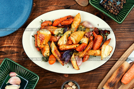 Healthy homemade roasted parsnip root, carrots and garlic on a vintage wooden background.. Baked parsnip root and carrots on a wooden table. Стоковое фото, агентство Ingram Publishing / Фотобанк Лори