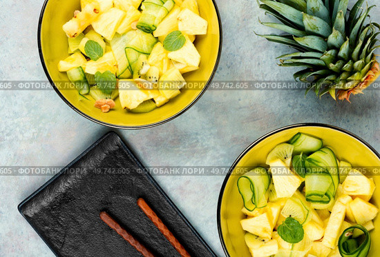 Healthy vegetarian salad with pineapple or ananas, nuts and cucumber in a bowl. Top view.. Fresh vegan salad with pineapple. Стоковое фото, агентство Ingram Publishing / Фотобанк Лори