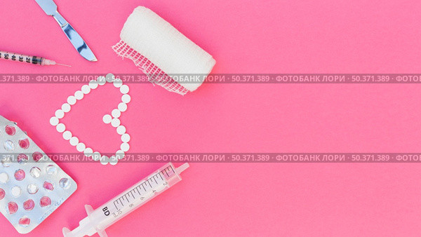 heart shape made with pills gauze syringe scalpel medicine blister pack pink background. Стоковое фото, агентство Ingram Publishing / Фотобанк Лори