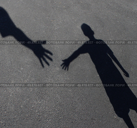 Helping Hand with a shadow on pavement of an adult hand offering help or therapy to a child in need as an education concept of charity towards needy kids and teacher guidance to students who need tutoring. Стоковое фото, агентство Ingram Publishing / Фотобанк Лори