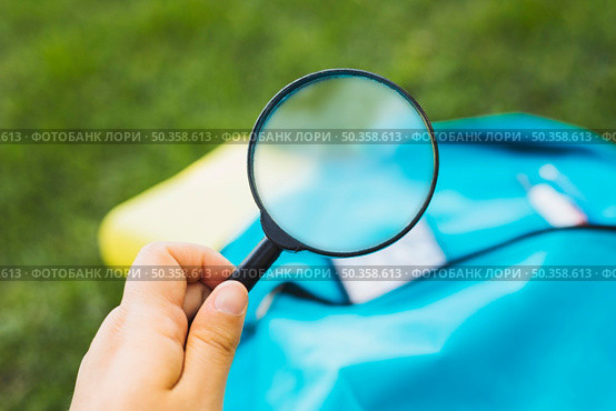 holding magnifier increases background backpack grass. Стоковое фото, агентство Ingram Publishing / Фотобанк Лори