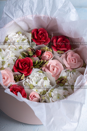 Home-made zephyr floristry arrangement featuring delicate pink, white, and red floral designs nestled in a soft tissue-lined container, showcasing artistry and creativity in dessert presentation. Стоковое фото, фотограф Ирина Ручушкина / Фотобанк Лори