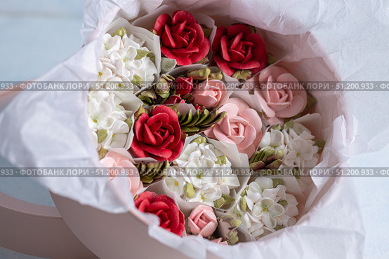 Home-made zephyr floristry arrangement featuring delicate pastel flowers and vibrant red roses, beautifully presented in a soft pink container with elegant wrapping. Стоковое фото, фотограф Ирина Ручушкина / Фотобанк Лори