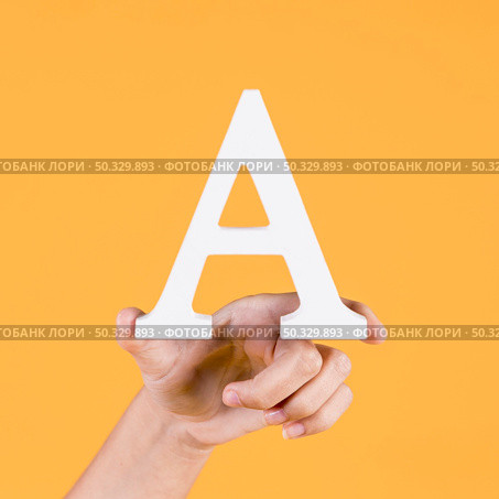 human hand holding up uppercase capital letter yellow background. High resolution photo. human hand holding up uppercase capital letter yellow background. High quality photo. Стоковое фото, агентство Ingram Publishing / Фотобанк Лори