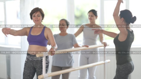 In ballet studio bathed in natural light, group of everyday women of different ages learning demi rond de jambe under guidance of female choreographer in beginners class. Стоковое видео, видеограф Яков Филимонов / Фотобанк Лори
