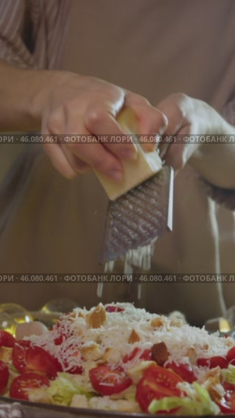 In the process of preparing a delicious vegetable salad, Gouda cheese is grated and rubbed into the salad. Slow motion. Vertical. Стоковое видео, видеограф Strunov David / Фотобанк Лори