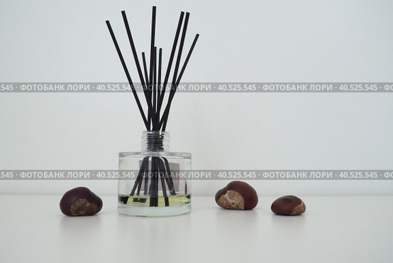 Incense sticks are dipped into a glass cubic vessel with essential oils. Interior decor. White background. Pleasant smell. The smell of winter chestnut. Chestnut fruits on a white background. Стоковое фото, фотограф Юлия Петровская / Фотобанк Лори