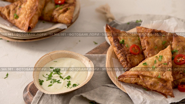 Indian samosas  - fried or baked pastry with savoury filling, popular Indian snacks, served in areca leaf dishes with spices on kitchen countertop. Стоковое фото, агентство Ingram Publishing / Фотобанк Лори