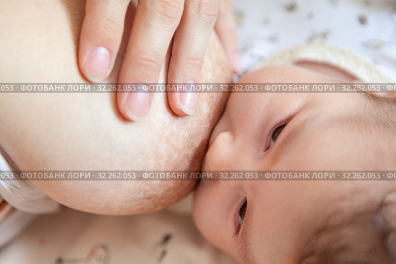 Infant feeding with female breast, close-up view at baby face and her mother breast. Стоковое фото, фотограф Кекяляйнен Андрей / Фотобанк Лори