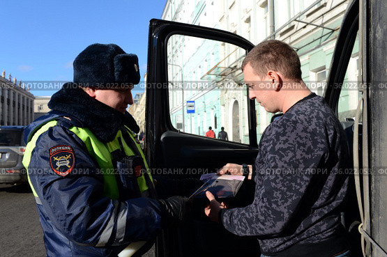 Инспектор дорожно-патрульной службы полиции проверяет документы водителя остановленного автомобиля (2017 год). Редакционное фото, фотограф Free Wind / Фотобанк Лори