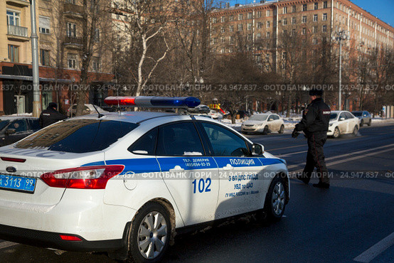 Инспектор ДПС производит проверку автомобилей около служебного автомобиля с включенным спецсигналом на набережной города (2017 год). Редакционное фото, фотограф Николай Винокуров / Фотобанк Лори