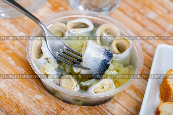 Invisible hand holds fork with pierced piece of salted herring fillet. Стоковое фото, фотограф Яков Филимонов / Фотобанк Лори