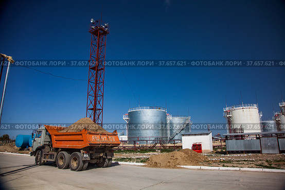Jambyl region, Kazakhstan - April 25 2012: Oil Refinery and Gas processing plant storage. Steel storage tanks and orange dump truck with ground. Редакционное фото, фотограф Alexey Rezvykh / Фотобанк Лори