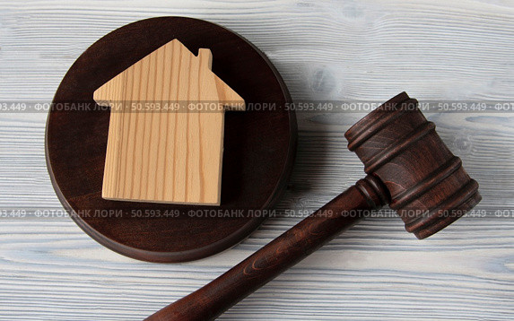 Judge’s hammer lies on a light wooden table against the background of the house. Стоковое фото, агентство Ingram Publishing / Фотобанк Лори