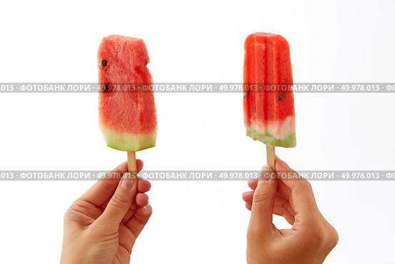 Juicy fresh slices of a watermelon on a stick hold female hands on a white background with a copy space. The concept of healthy berry ice cream lolly or dessert.. Hands of a girl holding two, appetizing, fresh slices of watermelon on a stick on a white background. The concept of healthy homemade ice popsicle with space for text . Summer dessert. Стоковое фото, агентство Ingram Publishing / Фотобанк Лори