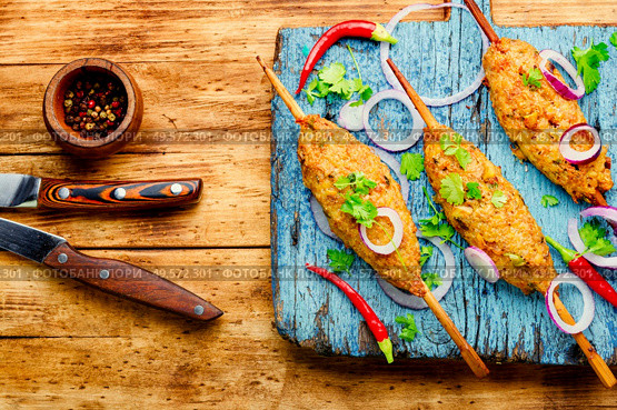 Juicy lula kebab made on wooden board.Minced meat on the grill. Lula kebab on stick. Стоковое фото, агентство Ingram Publishing / Фотобанк Лори