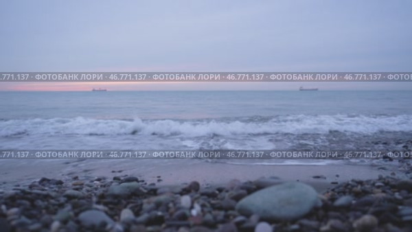 Каменистый пляж Черного моря в Батуми на закате Волны омывают каменистый берег Черного моря на фоне вечернего неба с розовыми облаками. Вдалеке видны два грузовых судна. Спокойный и умиротворяющий морской пейзаж. Стоковое видео, видеограф Анна Чижова / Фотобанк Лори