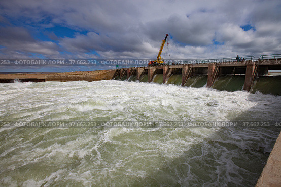 Kazakhstan, small Aral sea Kok-aral dam. Water discharge in flood. Open shutters. Yellow mobile crane and workers on dam. Стоковое фото, фотограф Alexey Rezvykh / Фотобанк Лори