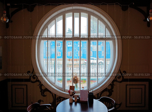 Kimry, Tver region, Russia – July 16, 2025: Cafe interior with a big round window in wooden house, called Teremok, used to belong to merchant Luzhin. Russian Art Nouveau architecture. Редакционное фото, фотограф Оксана Чаюн / Фотобанк Лори