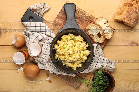 Композиция со сковородкой из вкусной яичницы-болтуньи, скорлупы, хлеба и зеленой капусты на деревянном фоне. Стоковое фото, фотограф Pixel_shot / Фотобанк Лори