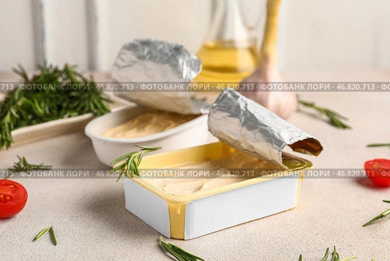 Коробки с обработанным сыром с розмарином, помидорами и чесноком на белом потертом столе у стены. Стоковое фото, фотограф Pixel_shot / Фотобанк Лори