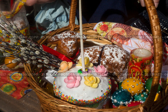 Корзинка с пасхальной выпечкой, веточками вербы и крашенными яйцами на столе у православного храма во время освящения в Великую субботу в городе Москве, Россия (2017 год). Редакционное фото, фотограф Николай Винокуров / Фотобанк Лори