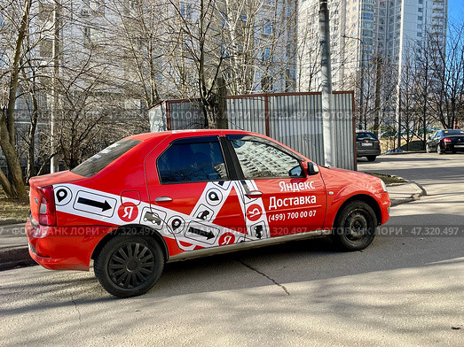 Красная легковая машина "Яндекс Доставка" во дворе жилого дома. Редакционное фото, фотограф Щеголева Ольга / Фотобанк Лори
