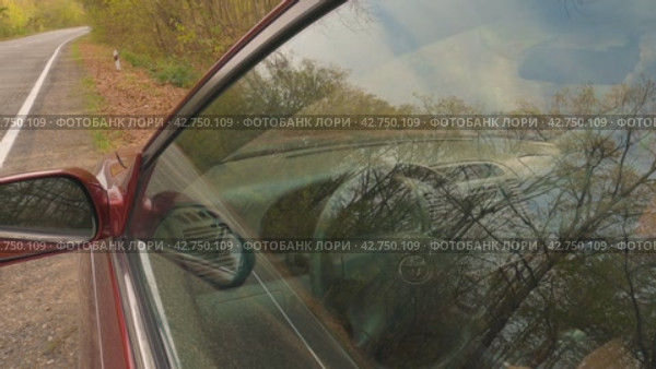 Крупный план красивого мужчины, открывающего дверь автомобиля и садящегося за руль. Заводит двигатель и выезжает на обочину. Проселочная дорога в осеннем лесу. Образ жизни, дорога, водитель. Россия, 15 ноября 2023 года. Редакционное видео, видеограф Воловодов Владимир / Фотобанк Лори
