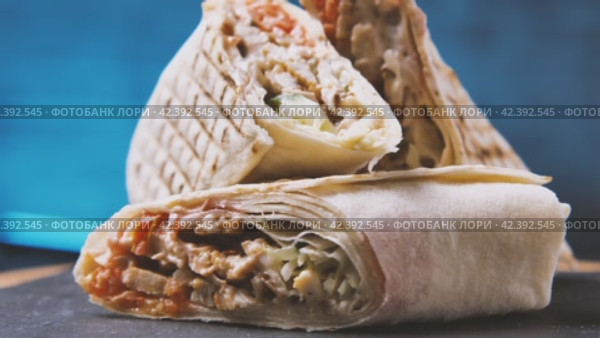 Крупный план шаурмы, разрезанной на три части на доске из черного камня. Вкусный арабский донер-кебаб. Традиционная турецкая еда. Греческий гирос. Камера вращается вокруг. Эффект параллакса. Стоковое видео, видеограф Воловодов Владимир / Фотобанк Лори