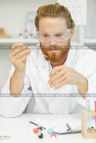 lab assistant in outfit holding a flask and pipette. Стоковое фото, агентство Ingram Publishing / Фотобанк Лори