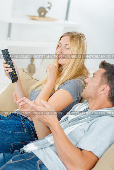 Lady holding remote control, telling partner to be quiet. Стоковое фото, агентство Ingram Publishing / Фотобанк Лори
