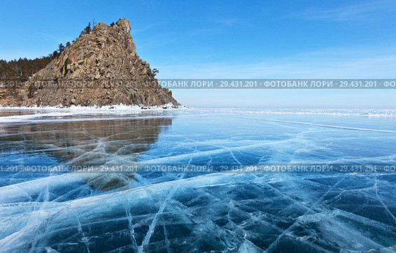 Lake Baikal. Beautiful winter landscape with transparent blue ice with cracks near the Big Bell Tower (Kolokolny Cape) Rock on a sunny frosty day. Стоковое фото, фотограф Виктория Катьянова / Фотобанк Лори