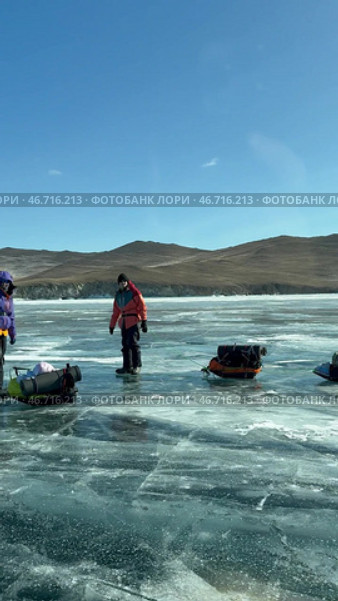 LAKE BAIKAL, KHUZHIR VILLAGE, OLKHON ISLAND, IRKUTSK REGION, RUSSIA -  February 28, 2025: Vertical video of hikers traveling on ice of frozen Maloe More with tents on sleds. Редакционное видео, видеограф Виктория Катьянова / Фотобанк Лори