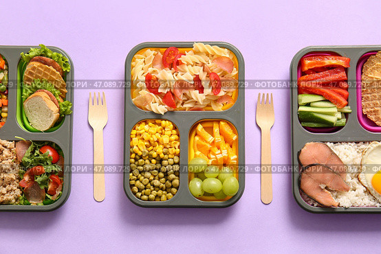 Ланчбоксы с разнообразной вкусной едой на лиловом фоне. Стоковое фото, фотограф Pixel_shot / Фотобанк Лори