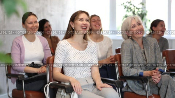 Laughing young girl participating in study session, sitting in auditorium with group of women and listening to lecturer. Стоковое видео, видеограф Яков Филимонов / Фотобанк Лори