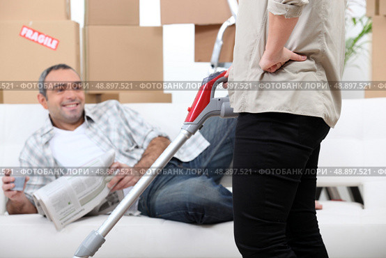 Lazy man watching his wife vacuum. Стоковое фото, агентство Ingram Publishing / Фотобанк Лори