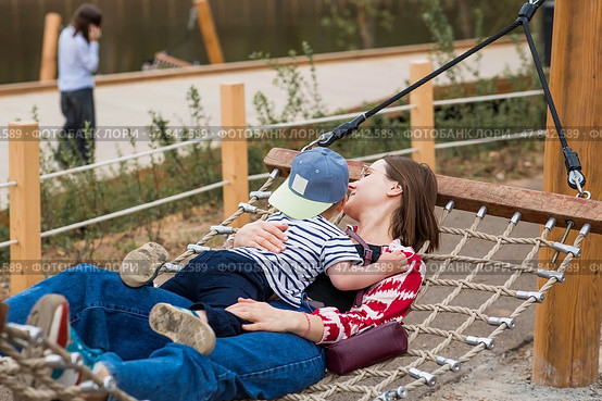 Lifestyle. A cute little boy and his mom are lying in a hammock on a modern outdoor playground. The concept of family privacy and entertainment. Стоковое фото, фотограф Photojuli / Фотобанк Лори