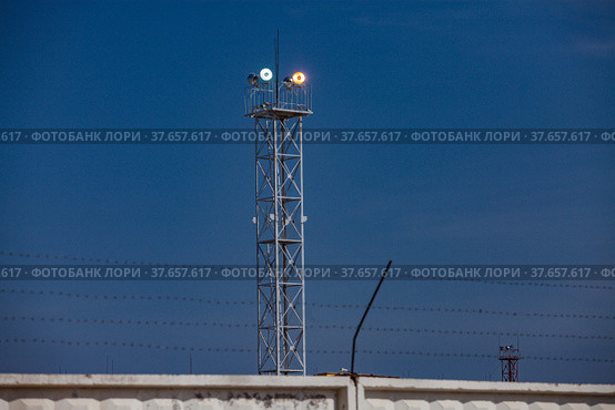Lighting mast with floodlight at oil refinery plant against blue sky background.. Стоковое фото, фотограф Alexey Rezvykh / Фотобанк Лори
