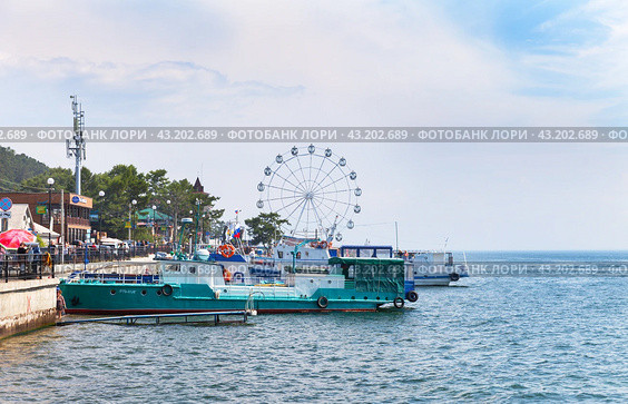 LISTVYANKA VILLAGE, IRKUTSK REGION, RUSSIA - August 03, 2023: Tourists like to relax in village of Listvyanka, take boat trips, dine in cafe overlooking Lake Baikal, and ride on observation wheel. Редакционное фото, фотограф Виктория Катьянова / Фотобанк Лори