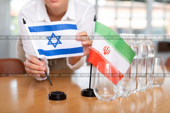 Little flag of Iran on table and flag of Israel put next to it by young woman. Стоковое фото, фотограф Яков Филимонов / Фотобанк Лори