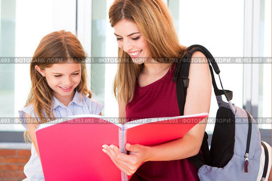 Little school girl showing sketchbook to her mother. Стоковое фото, агентство Ingram Publishing / Фотобанк Лори