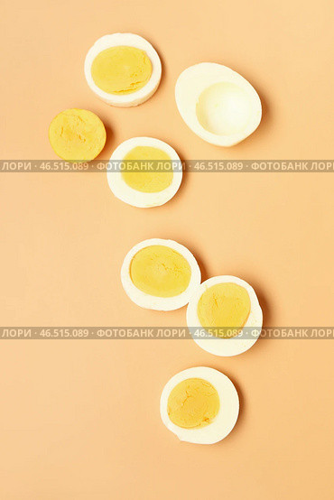 Ломтики вкусных отваренных яиц на оранжевом фоне. Стоковое фото, фотограф Pixel_shot / Фотобанк Лори