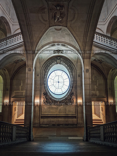 Louvre Palace symmetric architectural details of a hall with stone staircase, ornate railings, different corridors and a clock type window in center, Paris, France. Стоковое фото, агентство Ingram Publishing / Фотобанк Лори