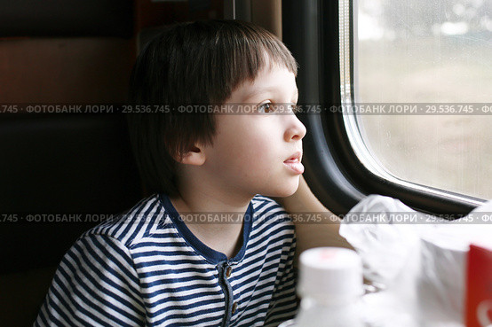Lovely little boy looks out of window in the train. Стоковое фото, фотограф ivolodina / Фотобанк Лори