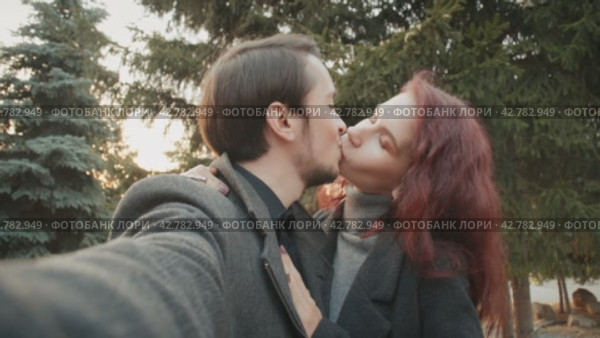 Lovely young couple is taking photo themselves outdoors in the autumn city park. Стоковое видео, видеограф EStarodubov / Фотобанк Лори