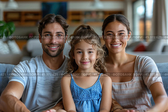 Loving young man hug his beloved wife and little daughter sit on couch in living room, happy people smiling looking at camera posing for photo picture. Exemplary family portrait, love and bond concept. Стоковое AI-изображение, AI-художник Ирина Михайличенко / Фотобанк Лори